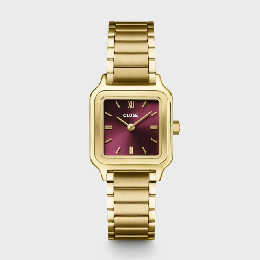 a gold coloured cluse watch with a  maroon face against a white background